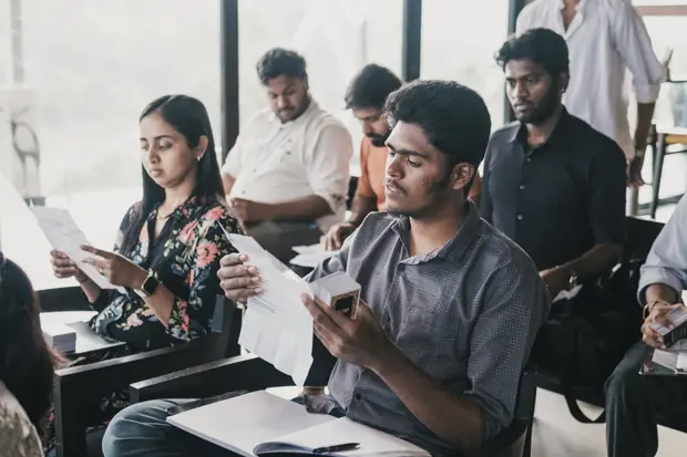 Founders seated in rows reading through printed worksheets