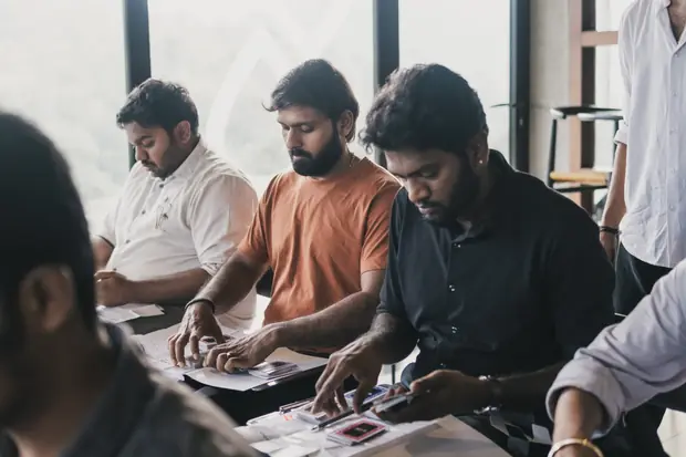 Three founders leaning over a table, sorting printed cards into groups