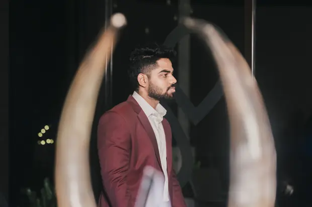 The speaker in a maroon blazer framed between two tall ivory sculptures