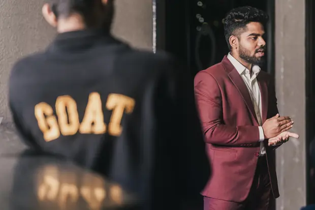 The speaker in conversation, a GOAT-lettered jacket in the foreground