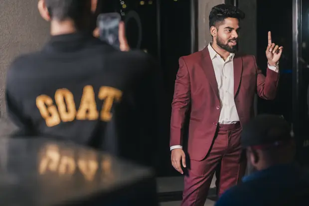 The speaker mid-gesture, a GOAT-lettered jacket blurred in the foreground